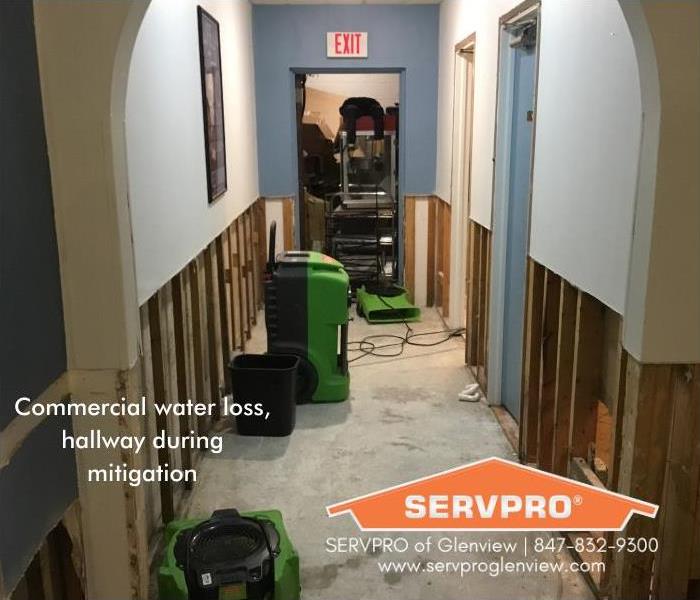 Commercial shop hallway during mitigation with dehumidifiers and fans