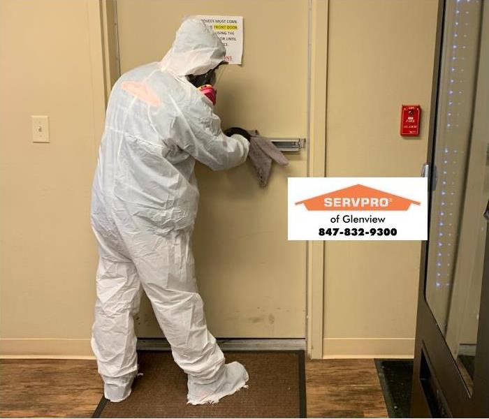 SERVPRO professional wiping down hallway during COVID-19 outbreak