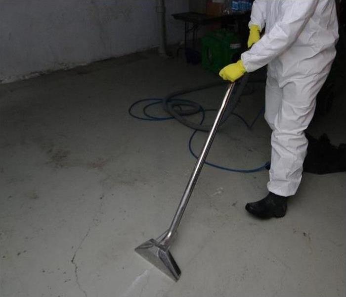 Image shows our technician using a vacuum water extractor in a customer's basement